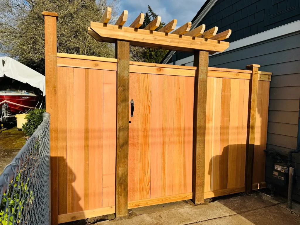 Cedar wood gate with pergola-style trellis top by driveway