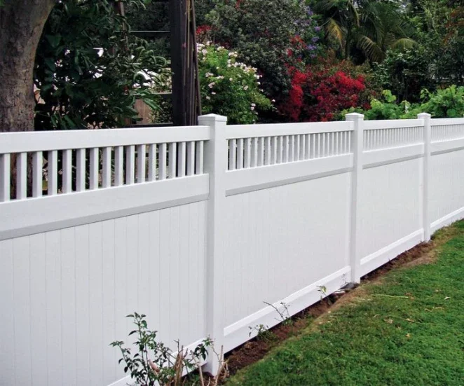 White vinyl privacy fence with framed spindle accent top in a garden.
